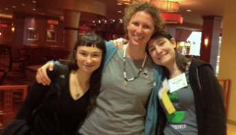 Three women with arms around each other in a hotel lobby at the 2014 NWRA symposium, one in a WRMD T-shirt.