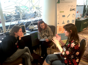 Three people in conversation at the WRMD vendor booth.