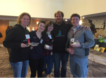 Five smiling people posing together in a conference hall.