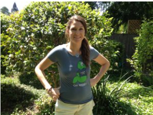 A woman in a garden wearing the blue-grey shirt, with the green WRMD worm logo on the chest.